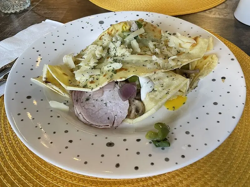 Real shop photo of a filled savoury crêpe on the shop's speckled plate